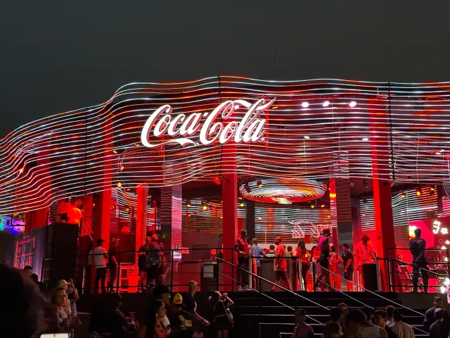 A fachada à noite, com as linhas de LED e os pilares vermelhos