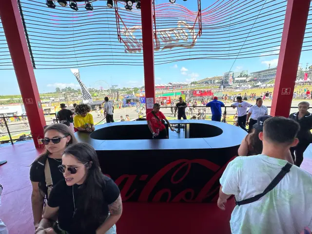 O bar curvo com o logo Coca-Cola e vista para o festival