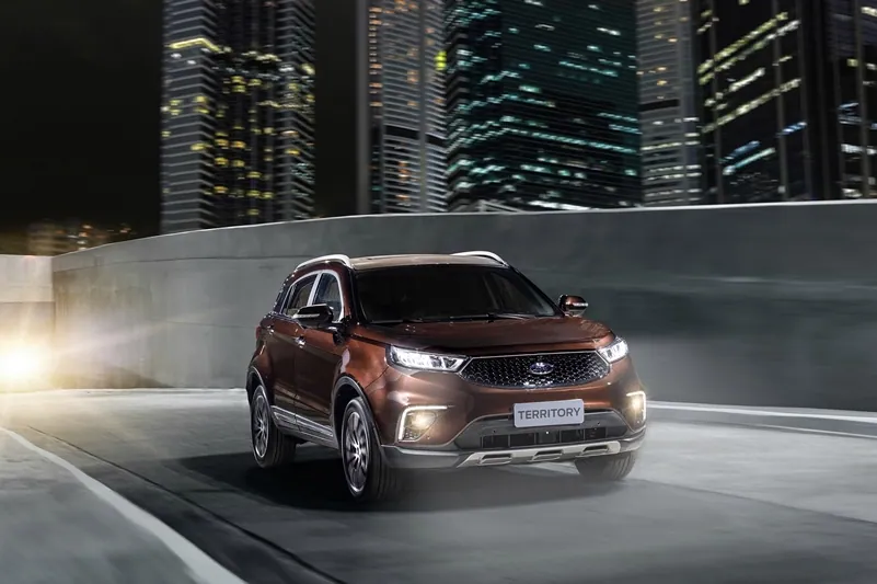 Um Ford Territory numa curva noturna, com a cidade ao fundo