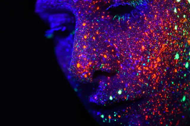 Referência visual: rosto com tinta glow sob luz negra