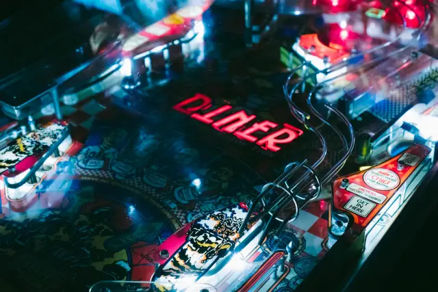 Referência visual: rampas cromadas, luzes e neon vermelho de um pinball