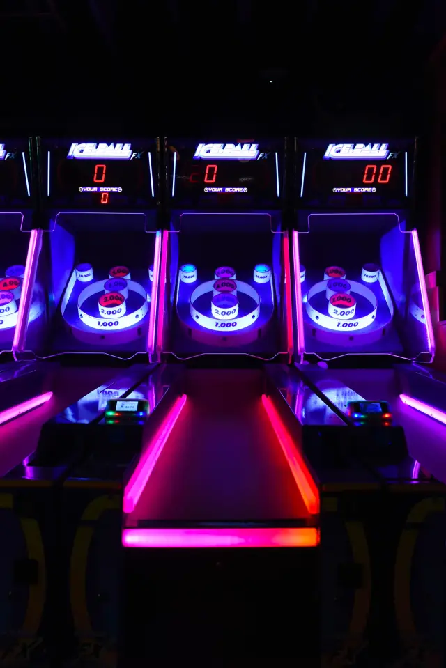 Referência visual: máquinas de skee-ball com neon e placares