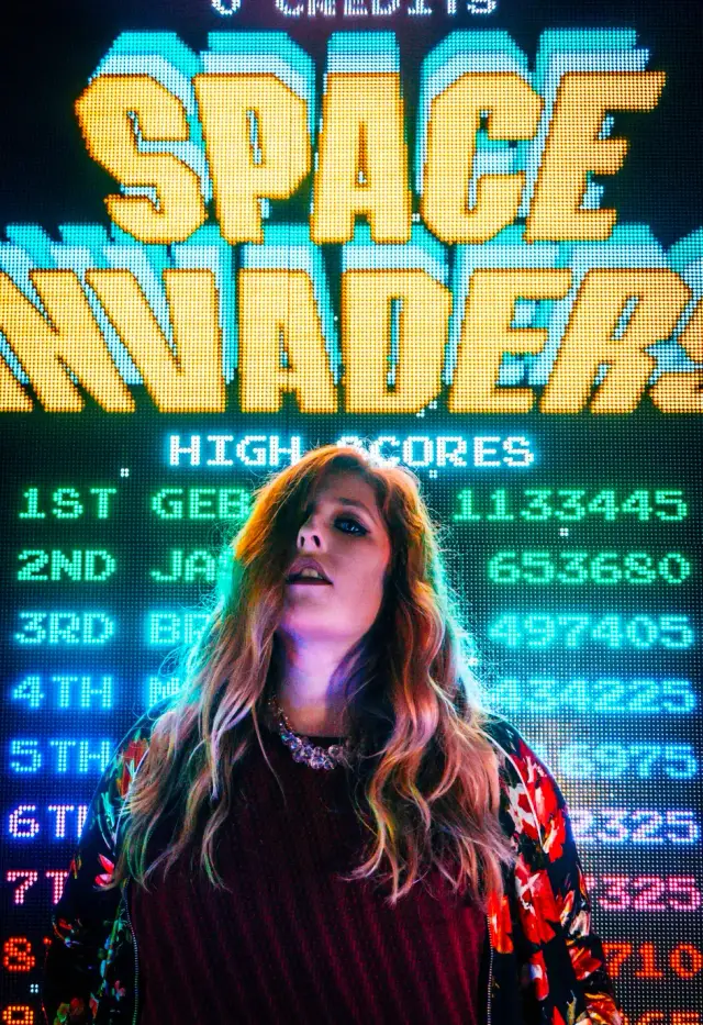 Referência visual: jovem diante do placar Space Invaders